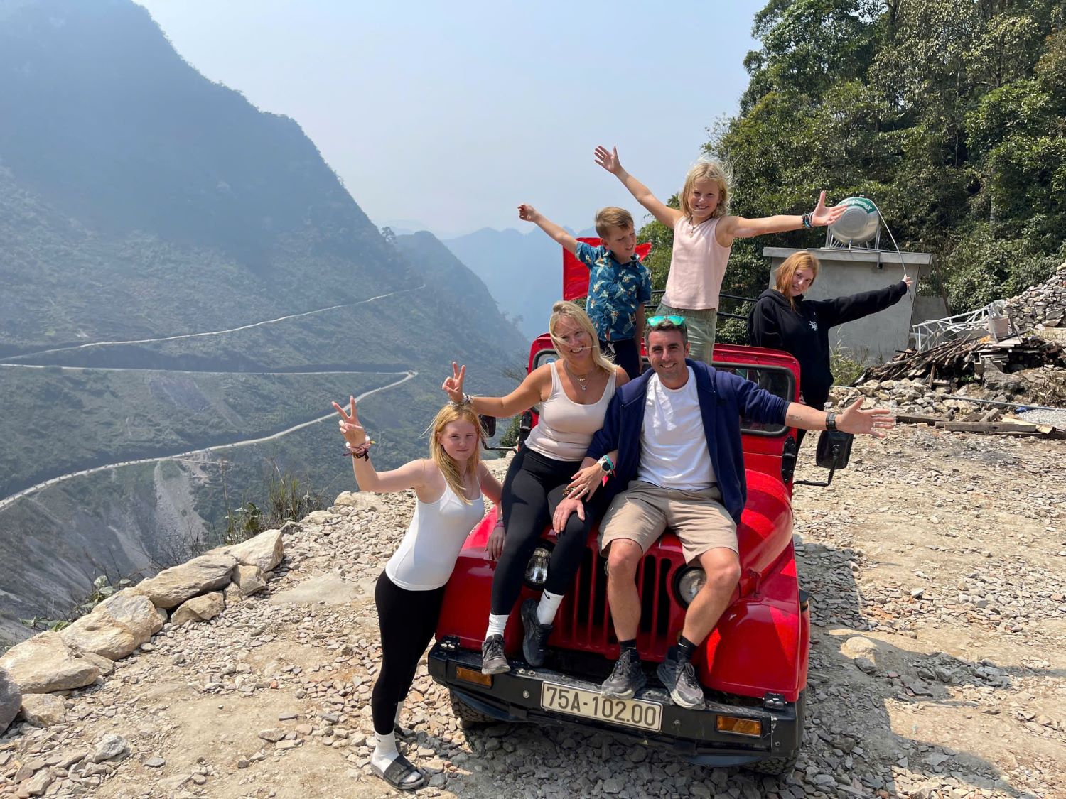 Jeep driving along Ma Pi Leng Pass with panoramic mountain views in Ha Giang